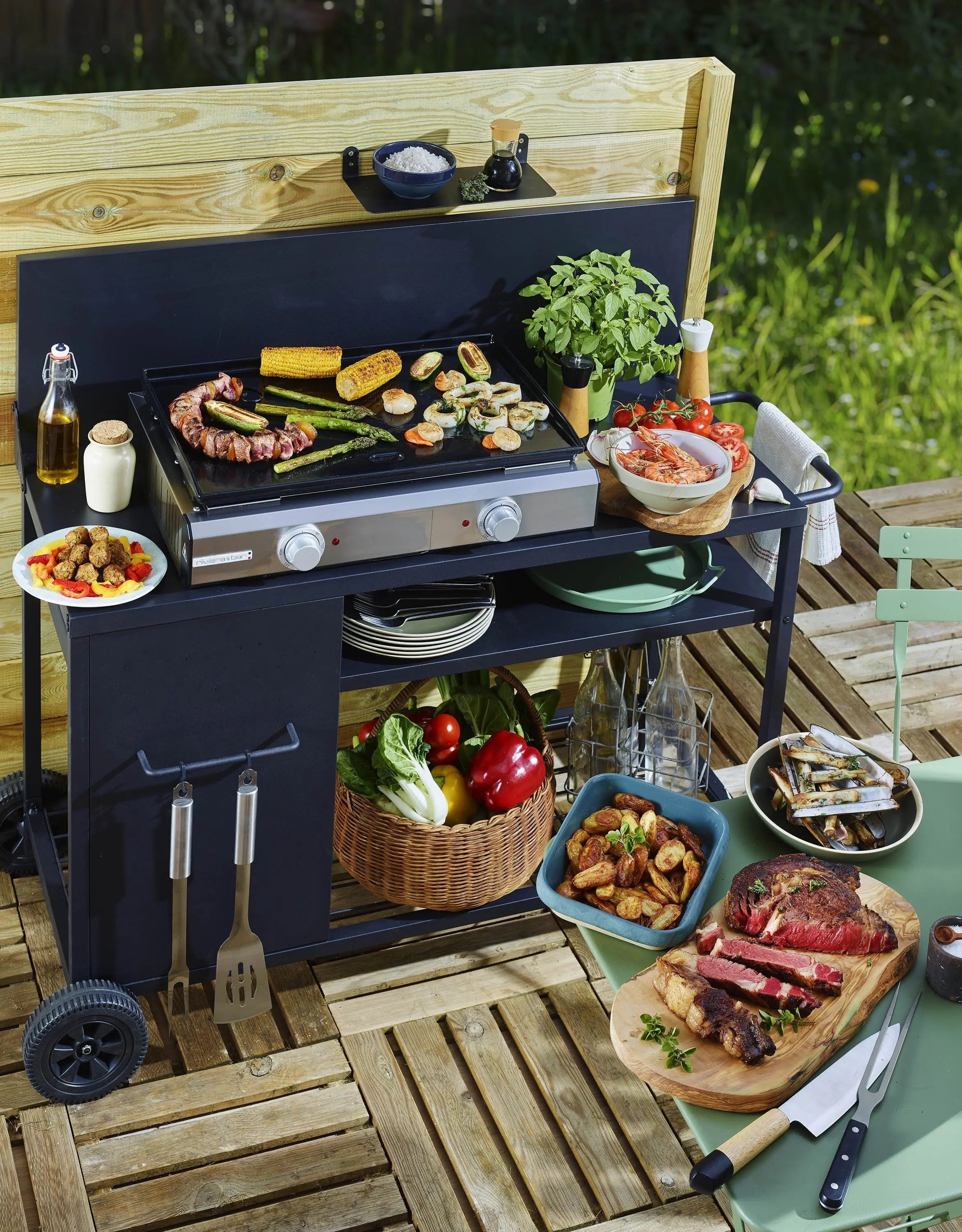 Gegrillte Leckereien auf einer Grillplatte im Freien mit Küchenwagen aus Holz.